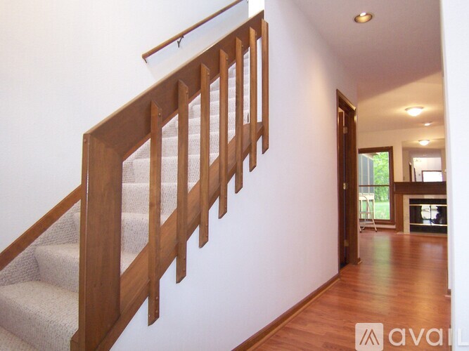 A wooden staircase with a carpeted runner leads to a bright living room.
