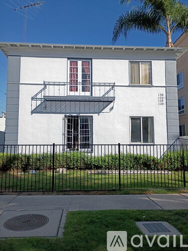 A white two-story house with a balcony on the second floor.