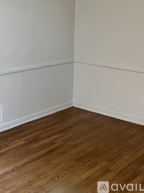 A room with wooden flooring and white walls.