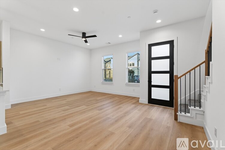 A spacious room with wooden flooring and a ceiling fan.