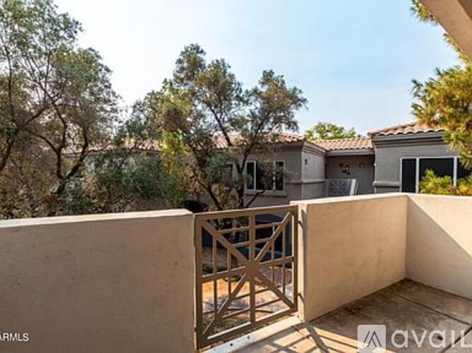 A balcony with a gate and a view of a house and trees.