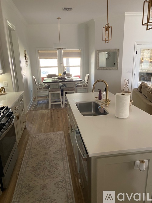 A kitchen with a sink, stove, and a dining table with chairs.