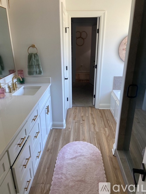 A bathroom with a sink, mirror, and wooden floor.