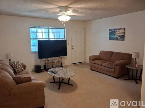 A living room with a flat screen TV, a couch, a chair, and a coffee table.