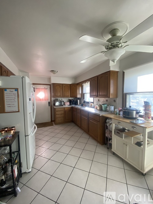 A kitchen with white tile floors and a white refrigerator.