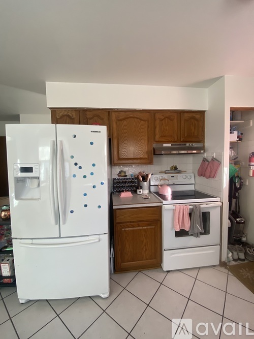 A white fridge with blue dots is in a kitchen with a white oven.