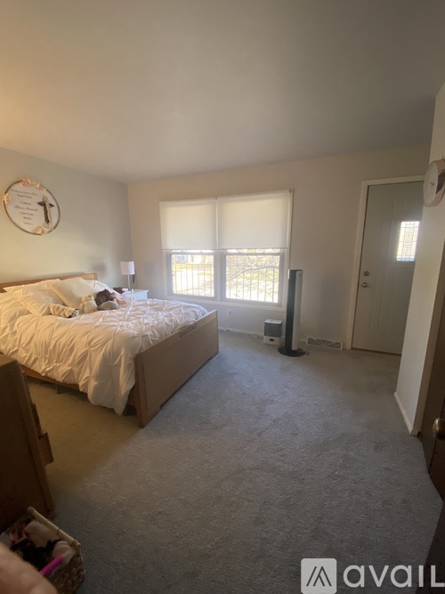 A bedroom with a bed, window, and a clock on the wall.