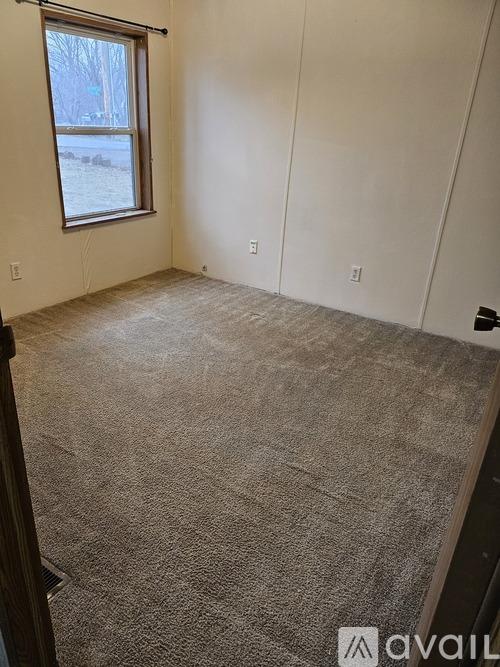 A room with a carpeted floor and a window.