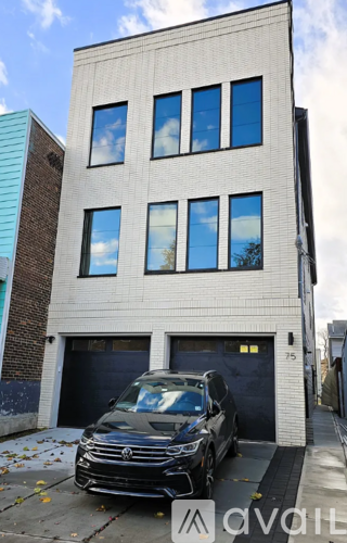 A black car is parked in front of a two-story building with a garage.