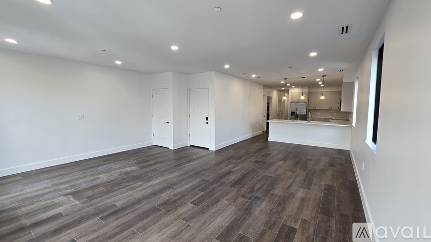 A spacious room with wooden flooring and white walls.
