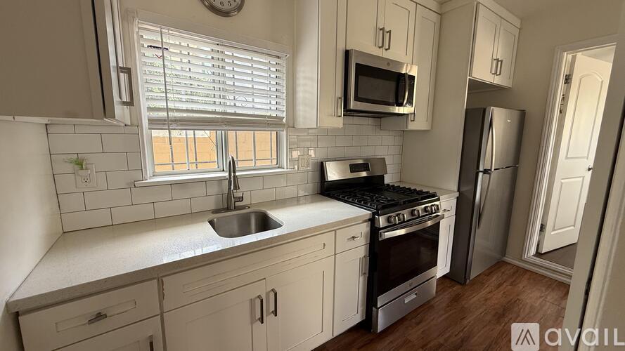 A kitchen with white cabinets and a stainless steel refrigerator.