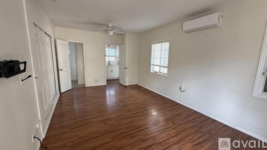 A spacious room with wooden flooring and white walls.