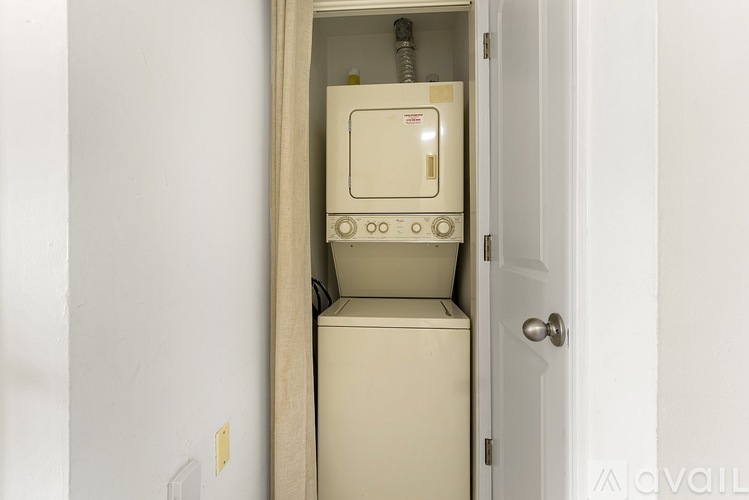 A tankless water heater is installed in a narrow space between a wall and a door.