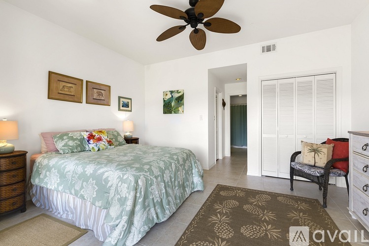 A bedroom with a bed, a ceiling fan, and a chair.