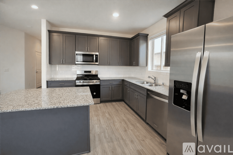 A modern kitchen with a stainless steel refrigerator and a granite countertop.