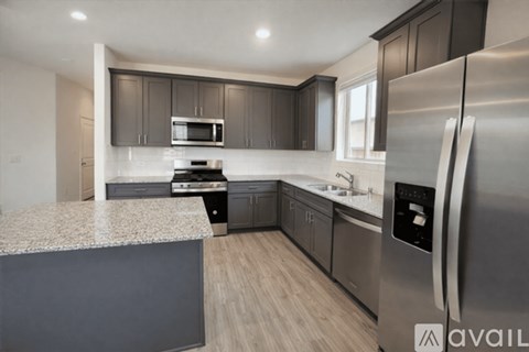 A modern kitchen with a stainless steel refrigerator and a granite countertop.