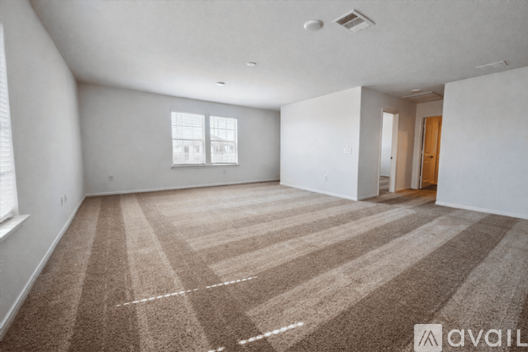 A large empty room with carpeted floor and white walls.