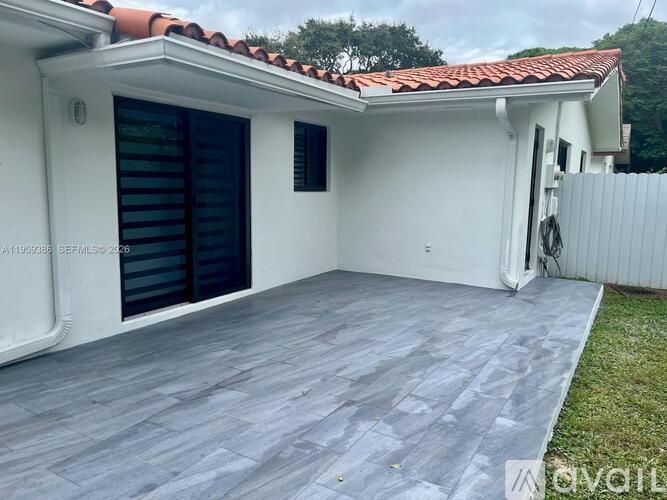 A white house with a red tile roof and a grey tiled patio.