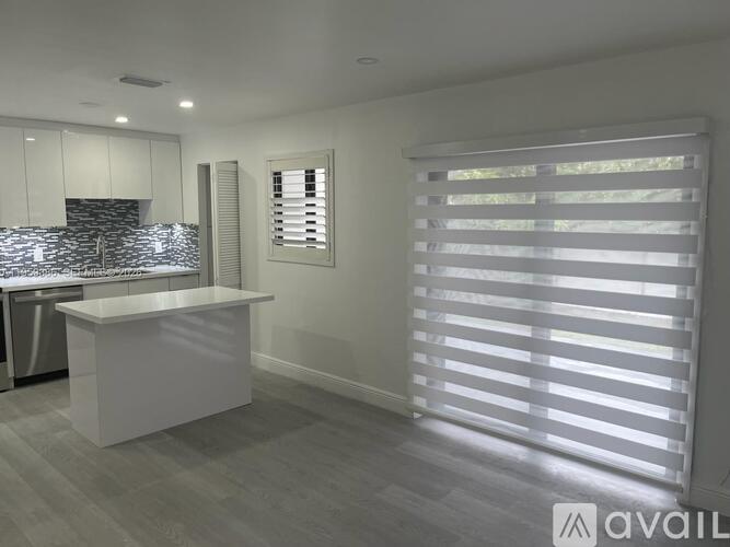 A modern kitchen with white cabinets and a large island.