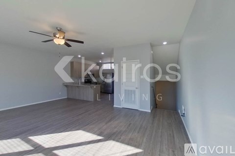 A spacious room with a ceiling fan and wooden flooring.