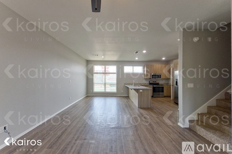 A spacious living room with wooden flooring and a staircase leading to another room.