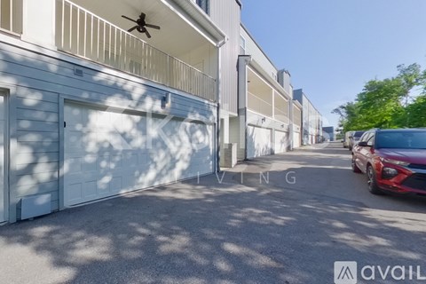 A red car is parked on the right side of a street lined with garages.