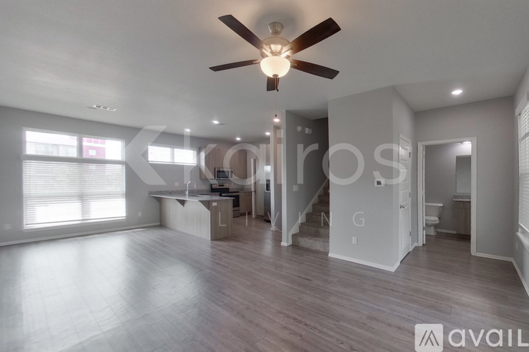 A spacious living room with a ceiling fan and hardwood flooring.