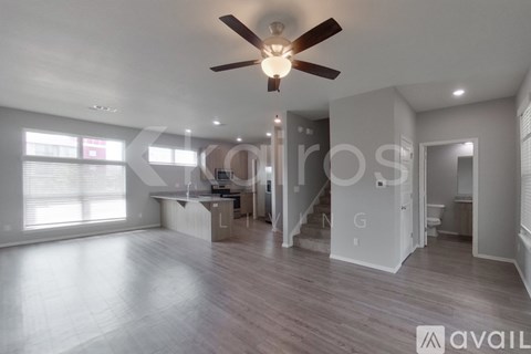 A spacious living room with a ceiling fan and hardwood flooring.
