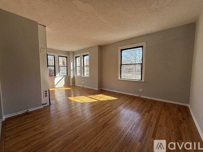 A spacious room with wooden flooring and a large window.