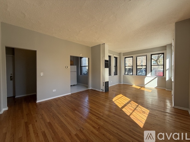 A spacious room with wooden floors and a large window.
