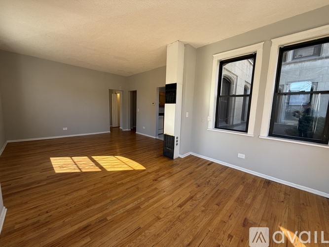 A spacious room with wooden flooring and a large window.