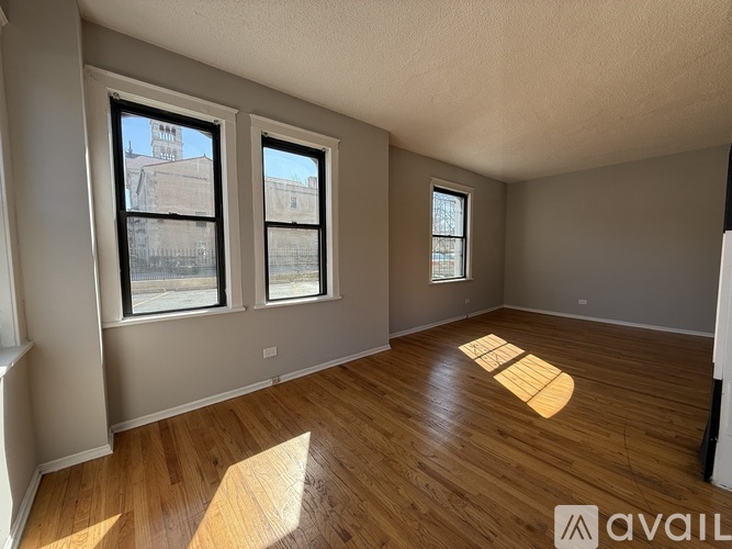 A room with wooden flooring and two windows.