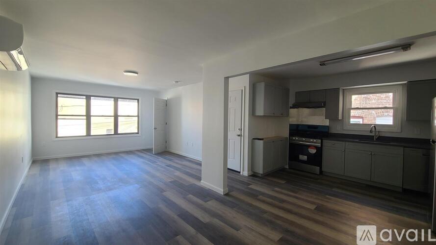 A spacious room with wooden flooring and a window.