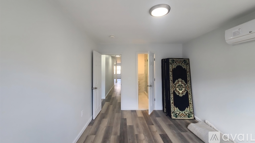 A hallway with a carpeted floor and a door with a black curtain on the right side.