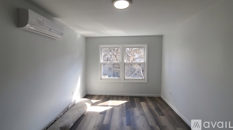 A room with a window and a wall-mounted air conditioner.