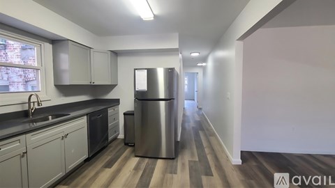 A kitchen with a stainless steel refrigerator and wooden flooring.