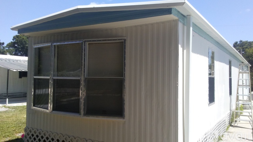 A white house with a dark roof and a window with blinds.