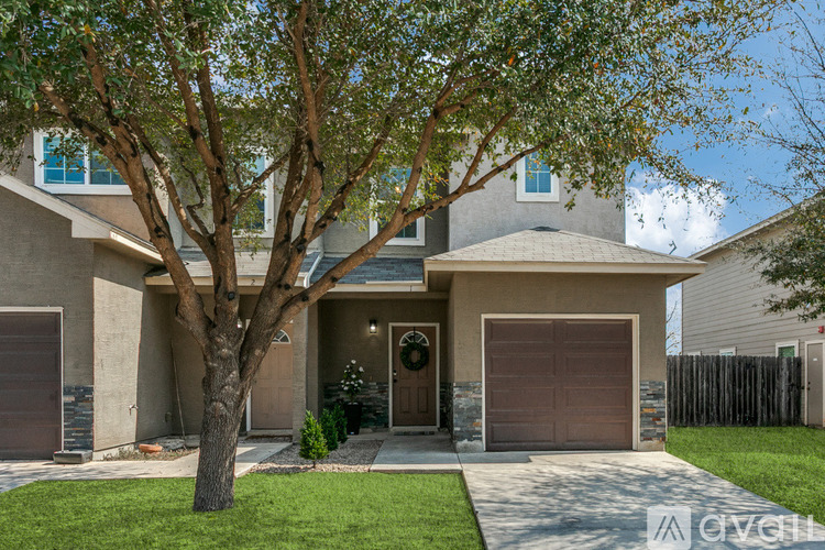 A house with a brown garage door and a tree in front.