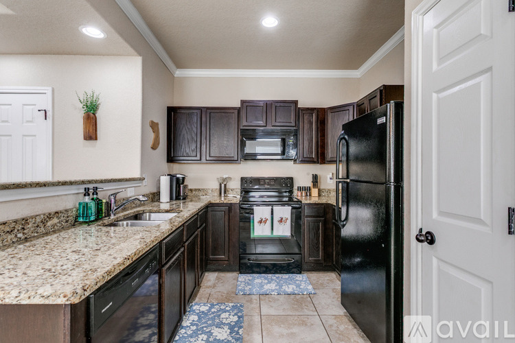 A kitchen with a black refrigerator and brown cabinets.