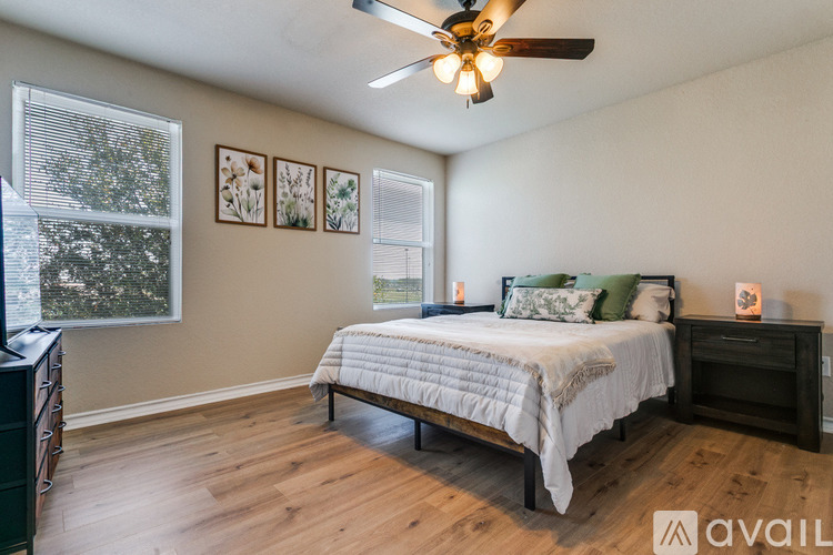 A bedroom with a bed, dresser, and a ceiling fan.