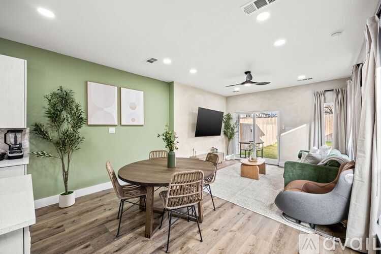A living room with a round table and chairs, a flat screen TV, and a ceiling fan.