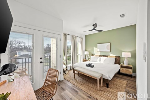 A bedroom with a bed, chair, and a ceiling fan.
