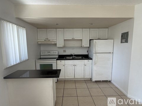 A kitchen with white cabinets and black countertops.