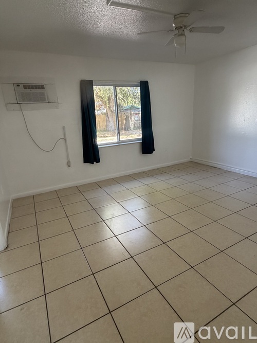 A room with a window and a fan on the ceiling.
