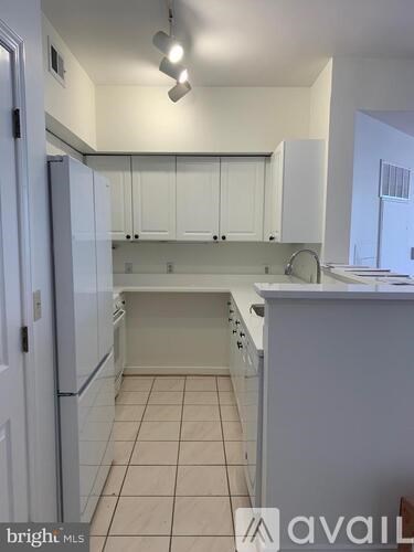 A kitchen with white cabinets and a white fridge.