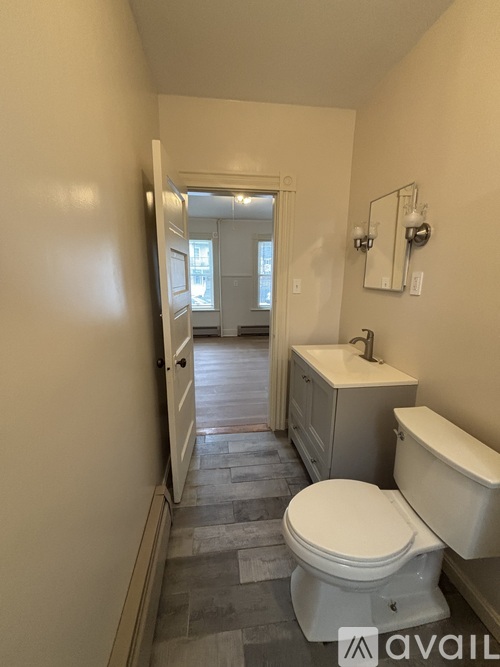 A bathroom with a toilet, sink, and mirror.