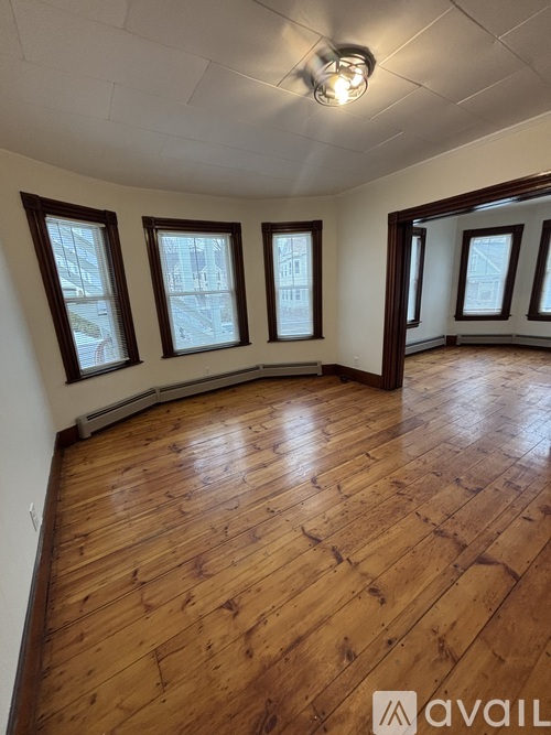 A room with wooden floors and three windows.