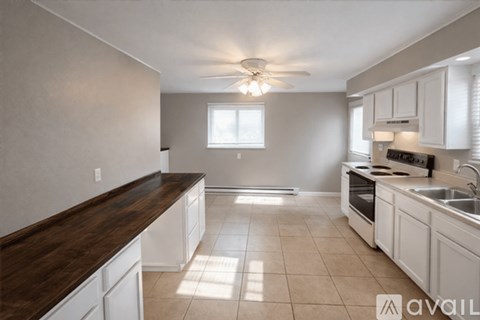 A kitchen with white cabinets and a brown countertop.