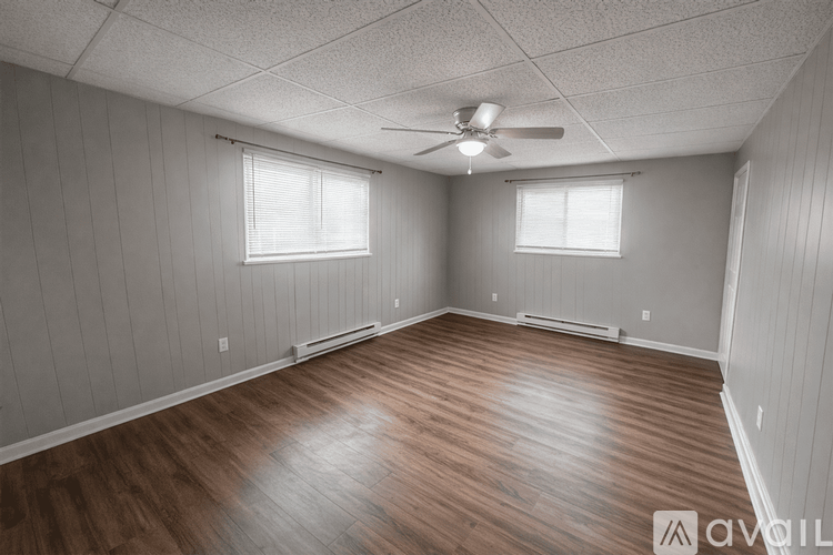 A spacious room with wooden floors and a ceiling fan.
