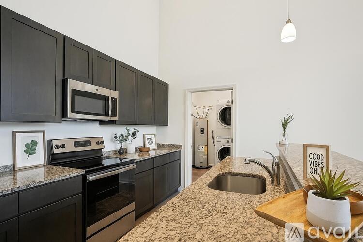 A kitchen with black cabinets and a granite countertop.